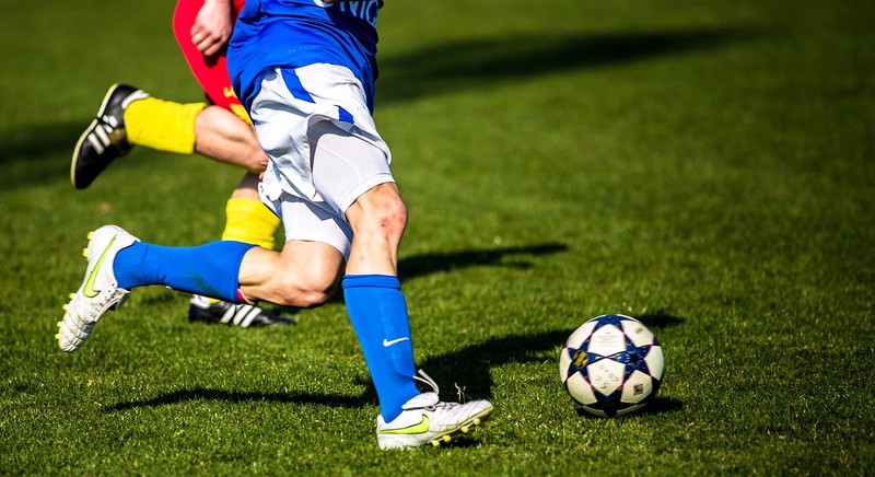 Fußballspieler werden hier im Zweikampf gezeigt