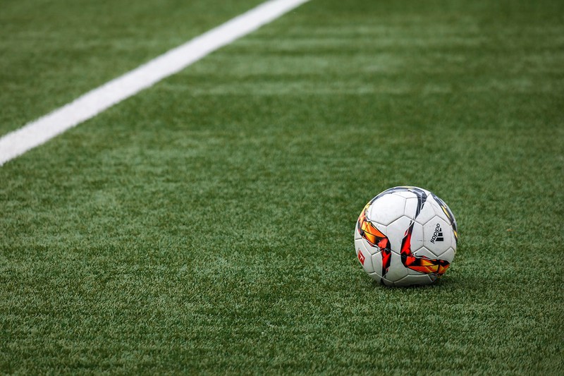 Fußballplatz aus Kunstrasen, auf dem ein Ball liegt