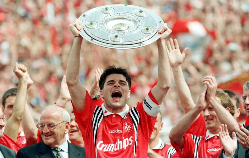 Der Fußballkapitän von Kaiserslautern von 1998 feiert den Sieg mit der Schale in der Hand.